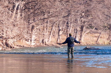 An angler casts his fly fishing rod for trout in the scenic Guadalupe River 11 miles below Canyon Lake dam where river fishing guides show people where the trout are in Texas USA