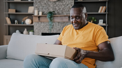 Surprised african adult man unpack parcel box american bachelor homeowner consumer birthday person...