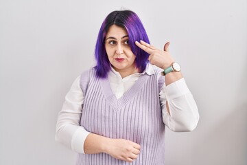 Obraz na płótnie Canvas Plus size woman wit purple hair standing over white background shooting and killing oneself pointing hand and fingers to head like gun, suicide gesture.