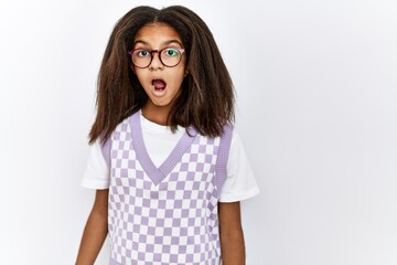Young african american girl standing over isolated background scared and amazed with open mouth for...