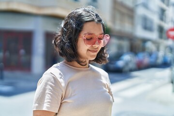 Young woman smiling confident wearing heart sunglasses at street