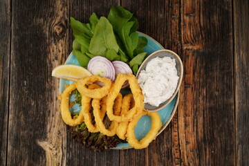Fried calamari with greens, onion, and tartare sauce. Calamari seafood with tartar sauce. Turkish name kalamar tava. Delicious seafood. 