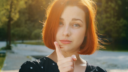 Female portrait outdoors in city dissatisfied redhead caucasian woman girl shakes index finger...