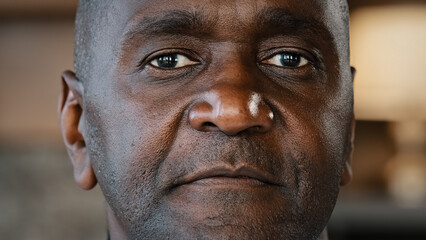 Close-up portrait african man concentrated human male wrinkled stubbly face american adult 50s...