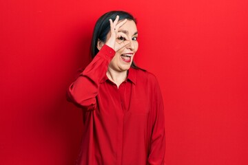 Middle age hispanic woman wearing casual clothes doing ok gesture with hand smiling, eye looking through fingers with happy face.