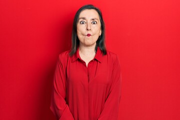Fototapeta premium Middle age hispanic woman wearing casual clothes making fish face with lips, crazy and comical gesture. funny expression.