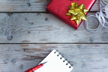 Gift box wrapped in bright green and red paper and note book. It is being prepared for delivery,...