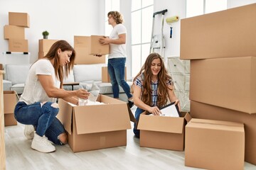 Mother and couple smiling confident unboxing cardboard packages at home