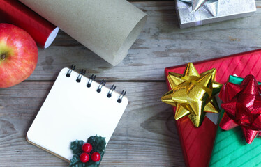 Gift box wrapped in bright green and red paper and note book. It is being prepared for delivery,...