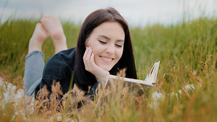 Young serene caucasian brunet woman girl lying on grass outdoors attractive smiling teenage student...