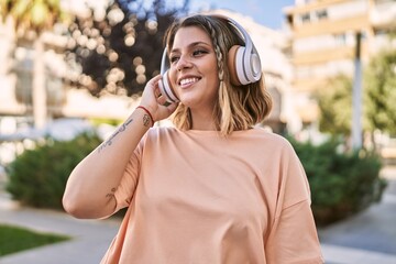 Young hispanic woman smiling confident listening to music at park