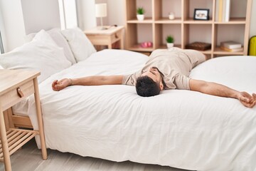 Young hispanic man smiling confident lying on bed at bedroom