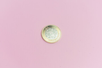 Moneda de 10 pesos mexicanos sobre fondo rosa.