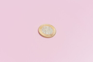 Moneda de 10 pesos mexicanos sobre fondo rosa.