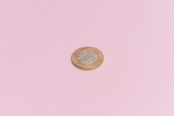 Moneda de 10 pesos mexicanos sobre fondo rosa.