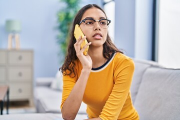 Fototapeta premium Young african american woman talking on the smartphone with worry expression at home