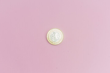 Moneda de 10 pesos mexicanos sobre fondo rosa.