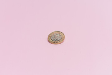 Moneda de 10 pesos mexicanos sobre fondo rosa.