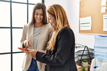 Fototapeta premium Mother and daughter business workers smiling confident using touchpad at office