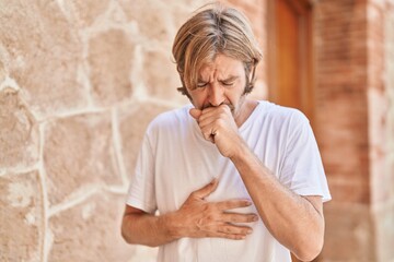 Young blond man coughing at street