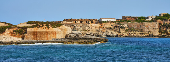 Naklejka premium Panorama of the coast of the island of Menorca with a ruined old fortification, Spain