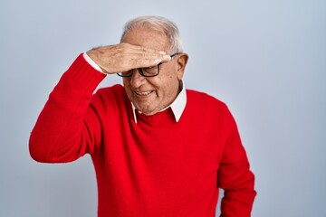 Senior man with grey hair standing over isolated background covering eyes with hand, looking serious and sad. sightless, hiding and rejection concept