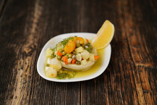 Artichoke appetizer with beans, potato, carrot, and lemon on a wood background. Traditional Turkish appetizers (meze) with olive oil.