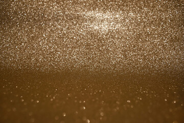 Sparkling golden glittery holiday background. Photo in perspective with selective focus.