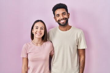 Young hispanic couple together over pink background with a happy and cool smile on face. lucky person.