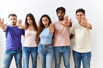 Group of young people standing together over isolated background doing stop gesture with hands...