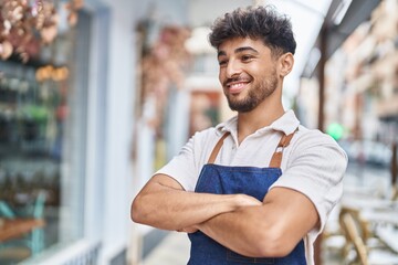 Young arab man waiter standing with arms crossed gesture at restaurant