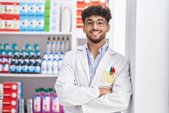 Young arab man pharmacist smiling confident standing with arms crossed gesture at pharmacy