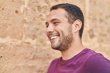 Fototapeta premium Young man smiling confident looking to the side over isolated brick background