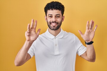 Arab man standing over yellow background showing and pointing up with fingers number nine while smiling confident and happy.