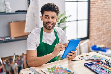 Young arab man artist smiling confident using touchpad at art studio