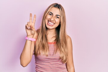 Beautiful hispanic woman wearing casual summer t shirt showing and pointing up with fingers number two while smiling confident and happy.