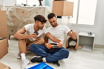 Two hispanic men couple drinking coffee choosing wall color at new home