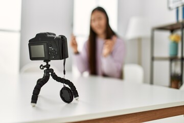 Young chinese girl having video call using camera sitting on the table at home.