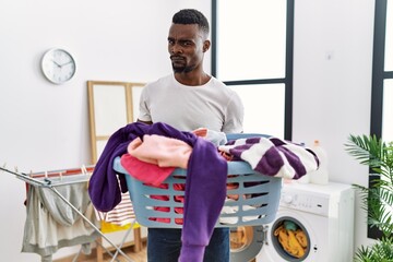 Young african man holding laundry basket skeptic and nervous, frowning upset because of problem....
