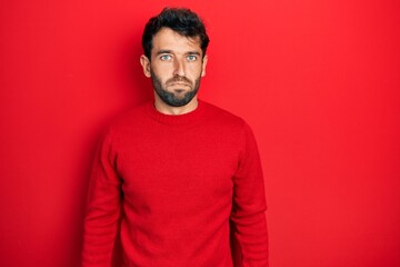 Fototapeta premium Handsome man with beard wearing casual red sweater depressed and worry for distress, crying angry and afraid. sad expression.