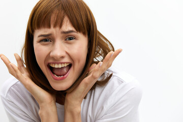 a close horizontal studio photograph of an alarmed, frightened woman with red hair, screaming loudly clutching her head from shock.