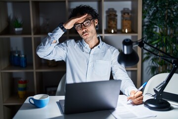 Obraz premium Hispanic man working at the office at night worried and stressed about a problem with hand on forehead, nervous and anxious for crisis