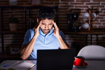 Hispanic man with beard using laptop at night with hand on head for pain in head because stress. suffering migraine.