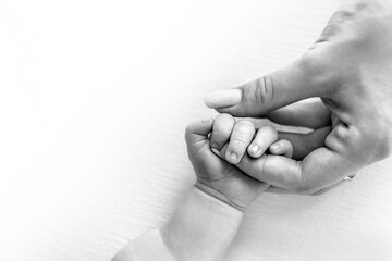 The born child holds the mother's finger. Premature baby. Black white photo.
