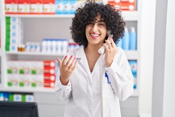 Young middle east woman pharmacist talking on telephone at pharmacy