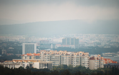 Obraz premium Scenic view of mountain town in foggy summer day.