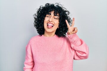 Young middle east woman wearing casual clothes smiling with happy face winking at the camera doing victory sign with fingers. number two.