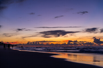 Fototapeta na wymiar People on Beach at Colorful Morning Twilight