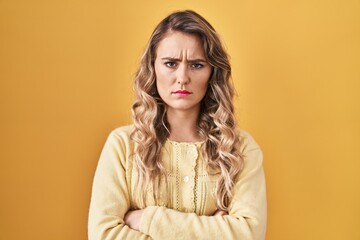 Young caucasian woman standing over yellow background skeptic and nervous, disapproving expression...