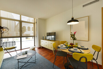 Living room of a vacation rental house with round wooden dining table with breakfast service with lots of fruit and orange juice